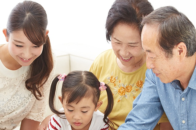 お誕生日新聞をみている家族