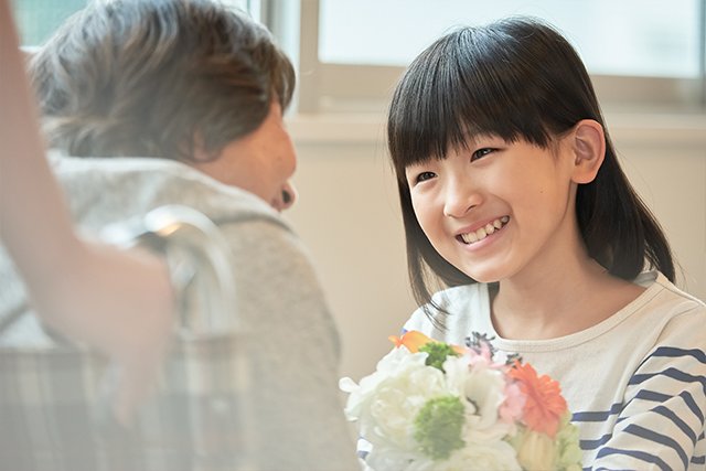 施設のおばあちゃんに花束を贈る孫